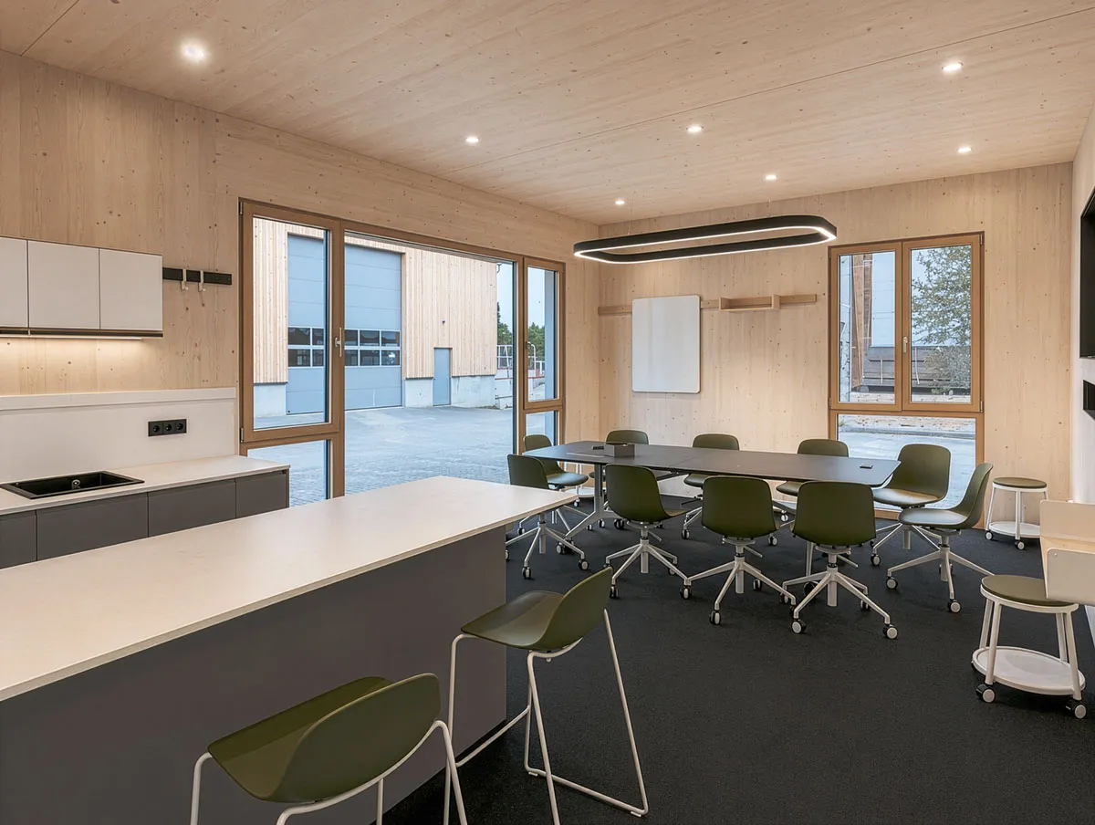 Besprechungsraum mit Küchenzeile, langem Tisch und Whiteboard an der Wandleiste