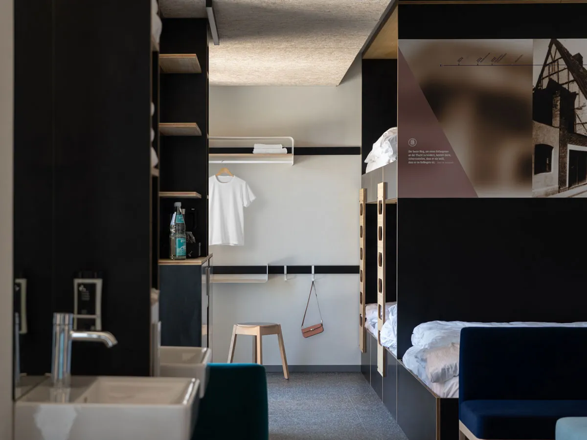 Garderobe mit Haken und Ablage an der Wandleiste, daneben das Etagenbett
