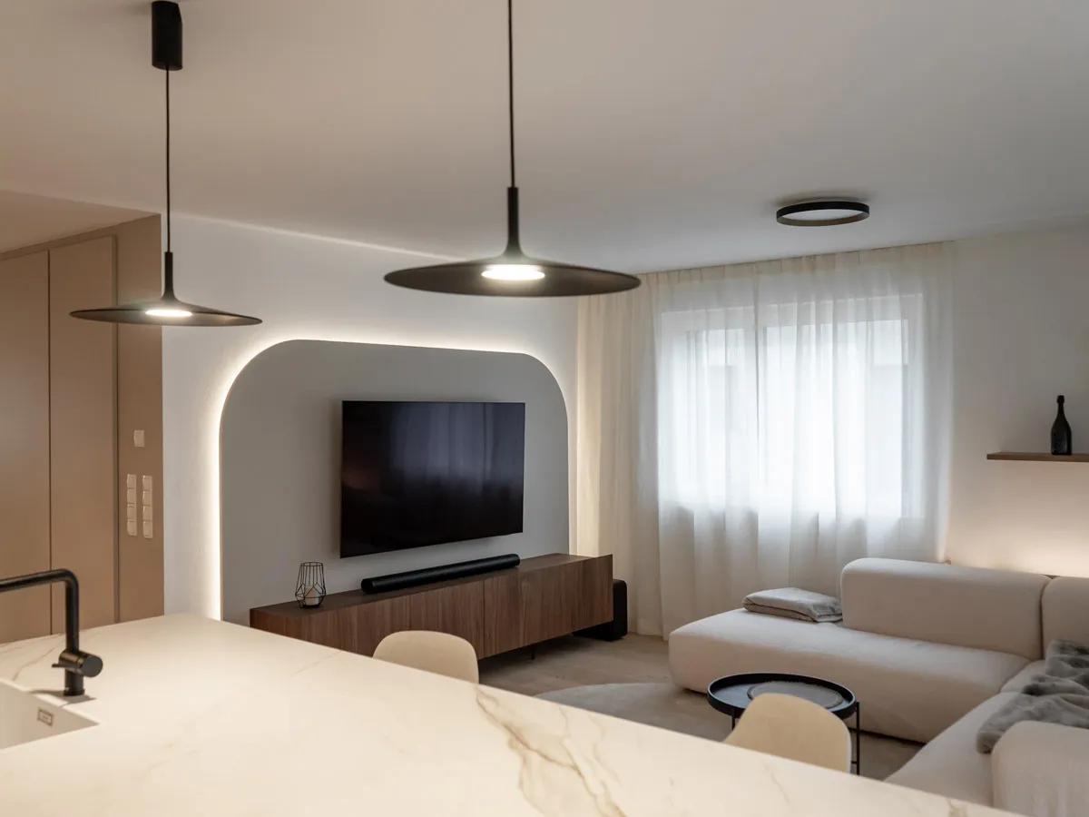 Wohnraum mit hinterleuchteter Bogennische, Fernseher und Nussbaum-Lowboard