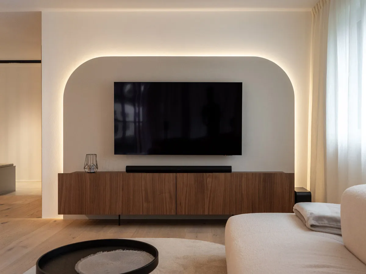 Hinterleuchtete Bogennische mit Fernseher über dem Nussbaum-Sideboard