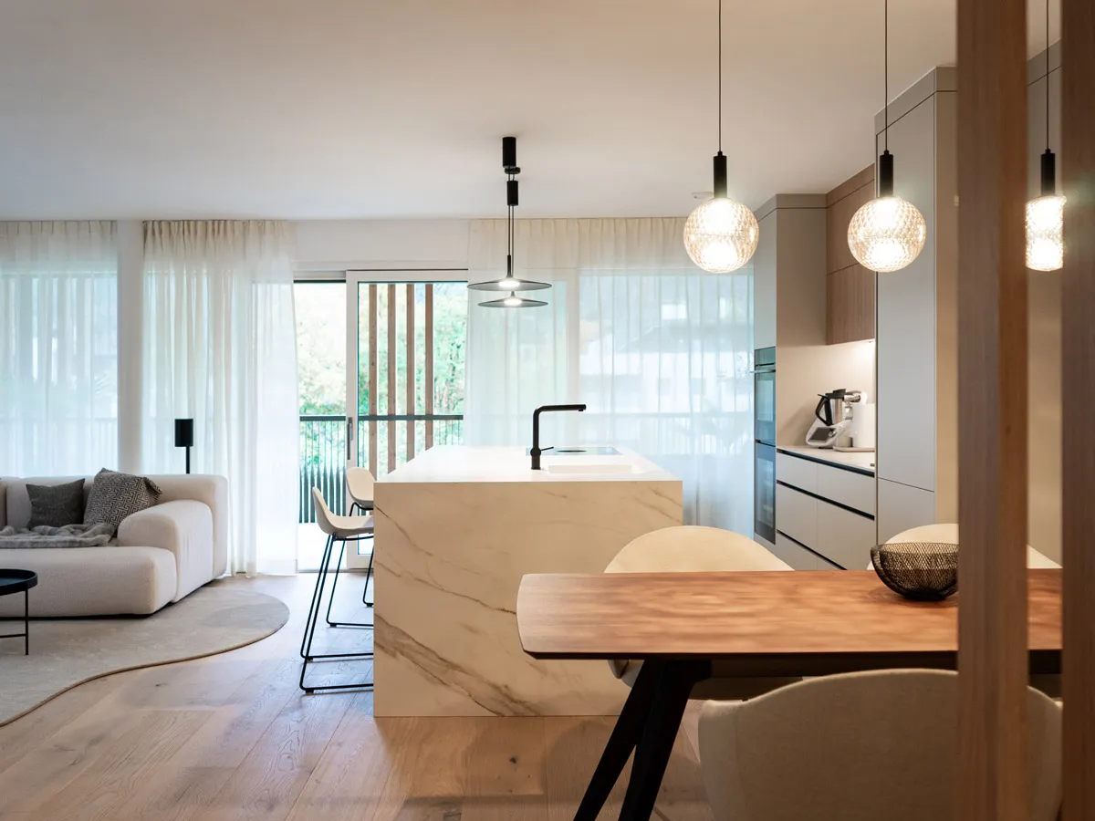 Offener Wohn-Essbereich mit Marmor-Kochinsel und Blick zum Balkon