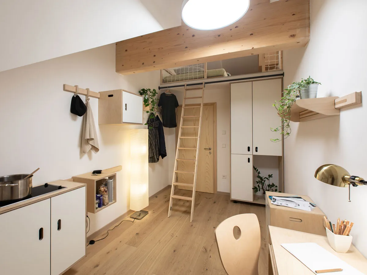 Zimmer mit Hochbett, Küchenzeile und Hängekasten an der Wandleiste