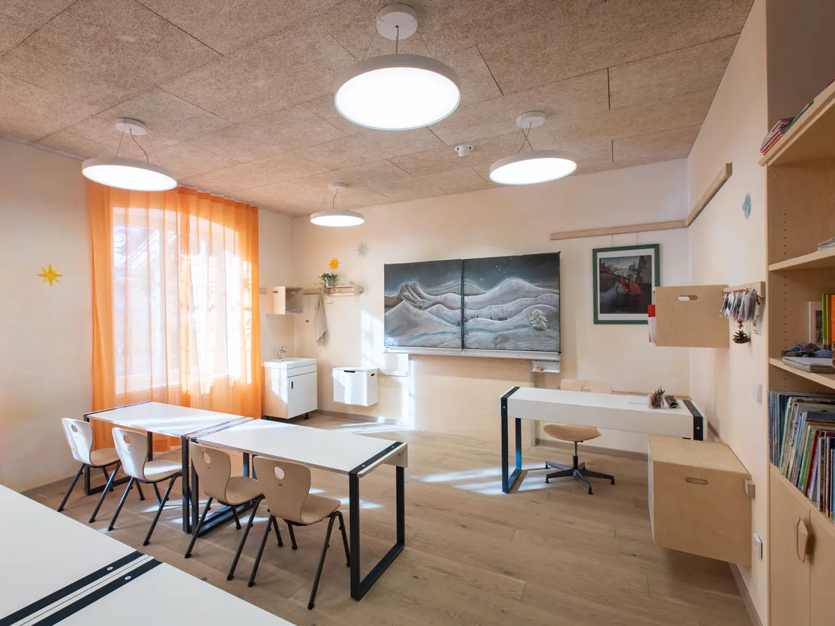 Klassenraum mit Tafel, Lehrerpult und Ablagen an der Wandleiste