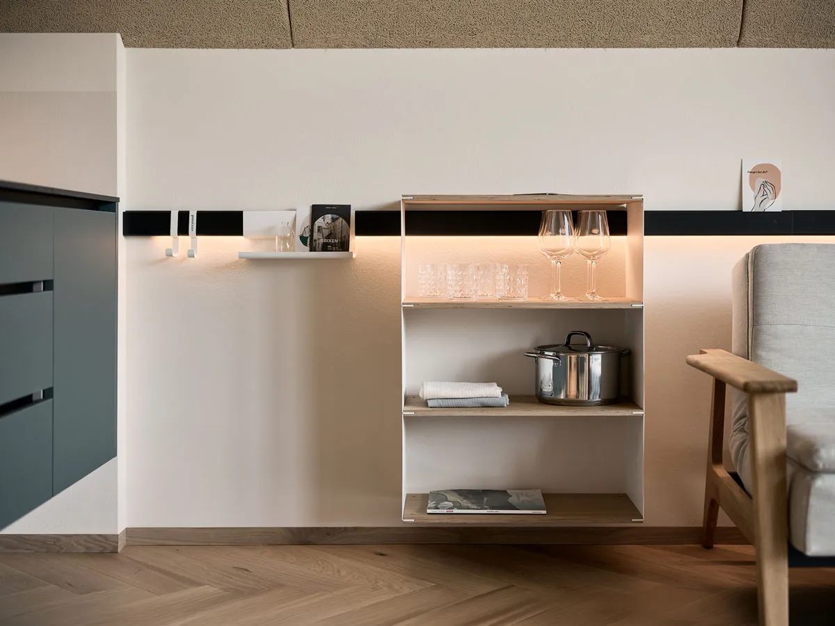 Hängendes Regalmodul mit Gläsern und Topf an der beleuchteten Wandleiste
