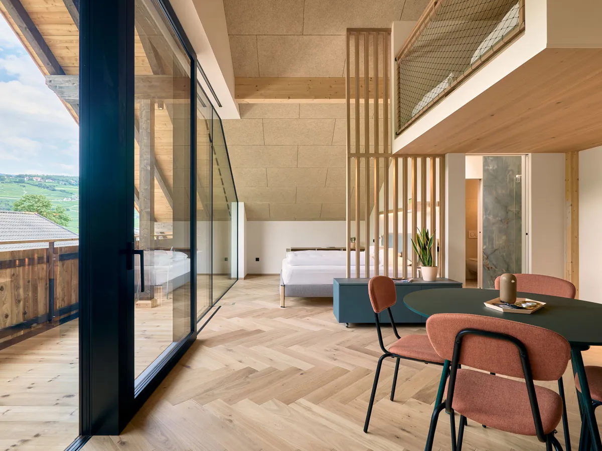 Maisonette-Wohnung mit Schiebetür zur Terrasse und Bett hinter dem Lamellen-Raumteiler